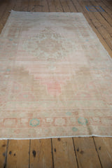 Distressed Oushak rug pile texture showing blush pink, beige, and pale turquoise.