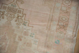 Distressed Oushak rug texture with geometric stepped motifs in faded blush and pale turquoise.