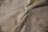 Distressed Oushak rug pile with geometric relief, faded blush, and pale turquoise motifs.