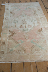 Distressed Oushak rug runner showing textured dusty rose, beige, and pale aqua floral motif.