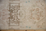 Distressed vintage Oushak rug detail: ivory field with abrash, pale coffee, and soft turquoise floral blossoms.