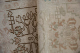 Close-up of folded vintage Oushak rug showing hand-knotted pile, subtle abrashes, and muted floral motifs.