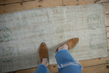 Distressed hand-knotted Oushak runner showing ivory and pale green floral patterns.