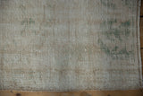 Distressed vintage Oushak rug texture showing wear to knot heads, ivory, beige, and pale green.