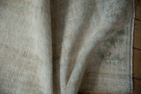 Distressed vintage Oushak rug texture with visible wear and subtle green tones.