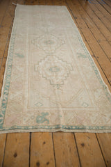 Distressed Oushak runner side showing pastel geometric patterns, main border, and worn pile.