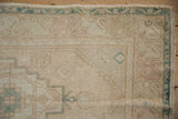 Distressed Oushak rug runner corner with muted ivory, beige pile and dusty sea foam geometric border.