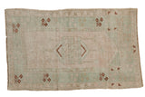 Distressed vintage Melas rug with faded floral medallion, soft pink and sea foam green tones.