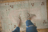 Distressed Melas rug corner featuring pale pink, sea foam, and copper floral motifs.