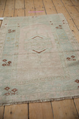Distressed vintage Melas rug pile showing faint foundation and pale pink, sea foam, copper brown patterns.
