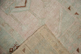 Distressed Melas rug pile with worn pale pink, sea foam green hues, folded to reveal beige foundation.