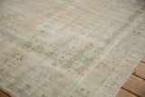 Distressed vintage Oushak carpet corner, showcasing faded mint green and pale brown geometric motifs.