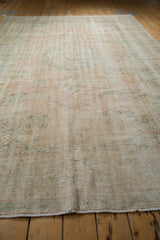 Distressed hand-knotted Oushak rug pile, showing knot head wear and muted rose, green tones.