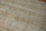 Worn pile, faded vinery, and exposed foundation of a distressed Oushak rug.