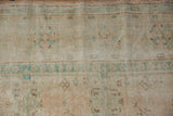 Worn distressed Oushak rug pile detail, showing foundation, faded dusty rose, and mint green.