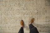 Distressed Oushak rug with mostly even wear, featuring faded ivory floral motifs.