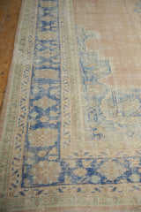 Distressed vintage Oushak carpet showing pale denim blue border pattern and visible foundation.