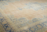 Distressed Oushak carpet with worn blush field and pale denim blue patterns.