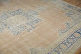 Distressed Oushak carpet close-up, showing worn pile, pale blue patterns, and visible foundation.