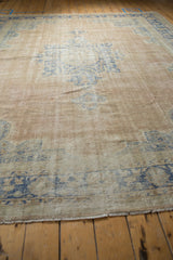 Distressed Oushak carpet's secured end with original fringe and worn texture.