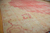 Vintage Oushak carpet's time-softened cherry red and ivory floral patterns, with visible texture.