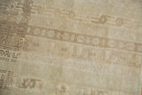 Distressed Oushak rug with worn pile texture, faded agricultural motifs in ivory and beige.
