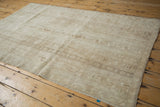 Distressed vintage Oushak rug pile with faded ivory and beige agricultural motifs.