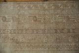 Distressed Oushak rug pile features faded ivory and beige agricultural motifs.