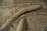 Folded vintage Oushak rug detail showcasing distressed pile, soft beige tones, and subtle patterns.