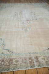 Detail of the distressed pile showing foundation through worn ivory and muted patterns.