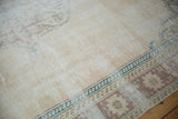 Distressed Oushak carpet texture with faded ivory, deep ocean green, and chestnut border.