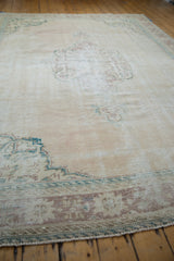Distressed vintage Oushak carpet border displaying worn ivory, deep ocean green, and pale chestnut patterns.