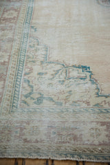Corner of distressed Turkish Oushak rug showing faded deep ocean green and chestnut borders.
