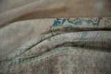 Close-up of distressed Oushak rug pile with muted ivory, ocean green, and chestnut patterns.