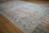 Vintage distressed Sparta carpet corner showing floral cross-section border with soft blush and blue.