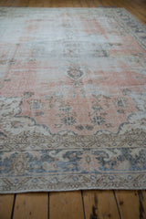 Distressed Sparta carpet texture, showing muted dusty rose and silver blue floral patterns with visible foundation.