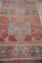 Distressed Oushak rug detail: geometric multi-medallion, abrashes, and worn knot heads in cinnabar and muted green.
