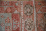 Distressed vintage Oushak rug with cinnabar red, beige, brown geometric relief patterns.