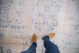 Worn texture and faded cobalt blue curvilinear motifs on vintage distressed Oushak rug.