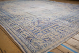 Distressed Oushak rug with low ivory pile, featuring cobalt blue border and floral vinery.