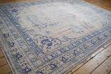 Worn corner of vintage Distressed Oushak rug, ivory field, faded cobalt blue vinery, geometric borders.