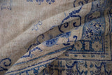 Distressed vintage Oushak rug showing worn pile and visible foundation with scrolling blue vinery.