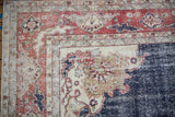Distressed vintage Sparta carpet corner with worn brick red, ivory, and navy border motifs.
