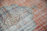 Distressed Oushak carpet with worn pile, displaying faded terracotta, ivory, and denim blue patterns.