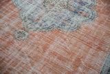 Distressed vintage Oushak rug with faded terracotta field and worn scalloped medallion.