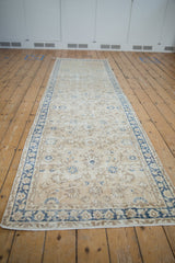 Distressed Sparta runner close-up with ivory field, cobalt blue floral motifs, and visible knot heads.