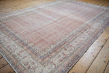 Distressed Sparta carpet's pale rust field with boteh motifs and ivory vine border.