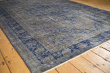 Angled detail of the distressed Oushak's low-pile texture and cobalt blue floral border.