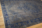 The distressed, low pile of an overdyed Oushak carpet with faded cobalt blue floral vinery.