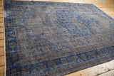 Decorative charcoal and cobalt blue tones on a distressed vintage Oushak rug viewed from an angle.